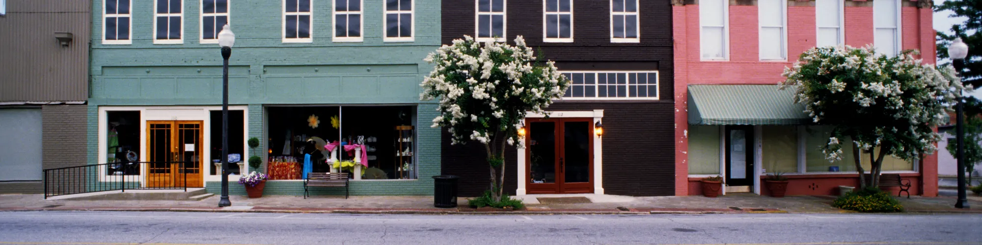 Colorful historic storefronts on a small town main street, featuring buildings with traditional architecture.